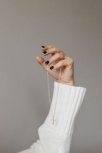 Kaboompics - Fingers Holding a Gold Chain Necklace Against a Neutral Backdrop