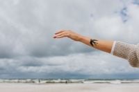 Kaboompics - Woman’s Swallow Tattoo Reaching Across a Cloudy Beach, Freedom and Lifestyle Concept