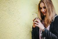 Kaboompics - Blonde woman in a black jacket and ripped jeans by a green handrail