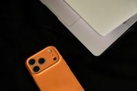 Kaboompics - Close Up of Orange Smartphone Beside Laptop on Black Leather