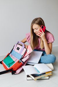 Kaboompics - Student Using Phone beside Backpack and Notebook