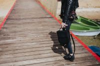 Kaboompics - Woman with a black bag and a can of coke walking on a wooden pier