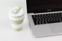 Kaboompics - Sage Green Collapsible Cup beside Laptop Keyboard in a Home Office