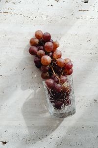 Kaboompics - Red Grape Bunch beside a Cut Glass on Travertine
