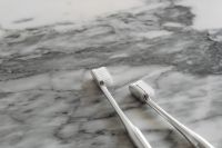 Kaboompics - Close-Up of Two White Toothbrush Heads and Chrome Handles on Veined Marble