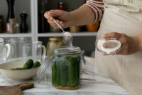 Kaboompics - Hands Sprinkling Salt over Cucumbers in a Glass Jar