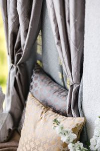 Kaboompics - Tied Grey Curtains and Neutral Patterned Pillows in a Balcony Nook