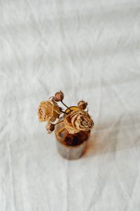 Kaboompics - Overhead Amber Bottle with Dried Roses for Neutral Floral Branding