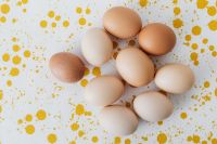 Kaboompics - Scattered Brown and White Eggs on a Yellow Speckled Background