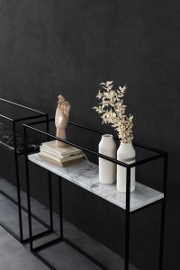 Kaboompics - Black Marble Console Decor with Stacked Books, Vases and Wooden Hand Sculpture