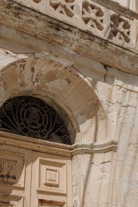 Kaboompics - Ornate Limestone Facade with Arched Iron Grille and Weathered Plaster