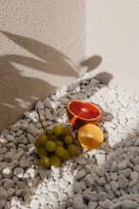 Kaboompics - Grapefruit, Orange and Grapes on White Pebbles with Shadows