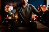 Kaboompics - Man Sitting on Sofa Surrounded by Glowing Christmas Lights