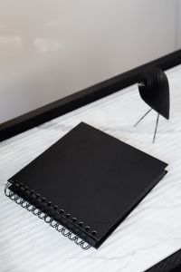 Kaboompics - Black Spiral Notebook with Wooden Bird and Architecture Books on Marble Desk