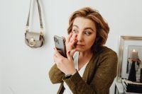 Kaboompics - At-Home Makeup Routine: Woman Applying Eye Makeup While Checking Her Phone