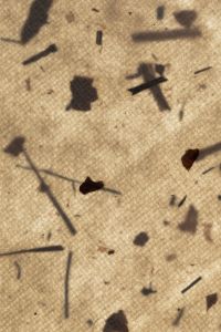 Kaboompics - Warm Beige Handmade Paper with Scattered Dark Fibers and Shadows, Organic Texture Background
