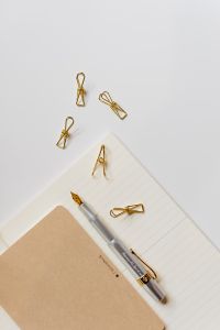 Kaboompics - Silver Fountain Pen and Gold Paper Clips Arranged on a Lined Notebook, Neutral Stationery Flat Lay
