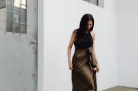 Kaboompics - Asian Woman Adjusting Brown Wrap Skirt in Black Sleeveless Top by White Wall