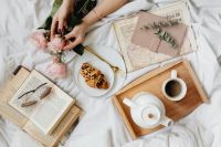 Kaboompics - Woman Arranging Pink Roses beside Coffee, Croissant and an Open Book in Bed
