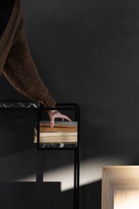 Kaboompics - Woman Arranging Books on a Black Marble Console Against a Charcoal Accent Wall
