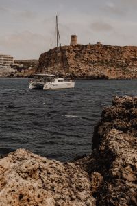 Kaboompics - White Catamaran Sailing Past a Rocky Maltese Headland