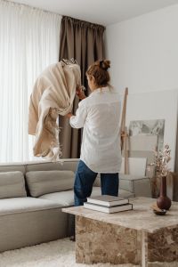 Kaboompics - Woman Organizing a Blanket on a Living Room Sofa