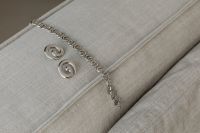 Kaboompics - Silver Chain and Spiral Earrings on a Sofa