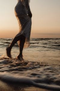 Kaboompics - Faceless Woman Walking Through Waves at Golden Hour