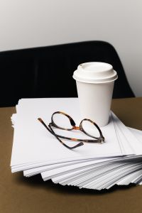 Kaboompics - Takeaway Coffee Cup and Tortoiseshell Glasses on Stacked White Paper, Minimal Office Desk Still Life