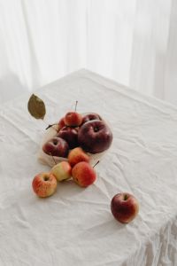 Kaboompics - Red Apple with Dried Leaves on a Round Marble Cake Stand, Minimal Neutral Food Background