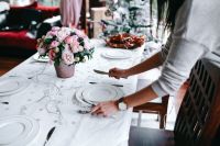 Kaboompics - Hands Setting White Plates and Cutlery on a Christmas Table