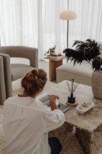 Kaboompics - Woman Reading Beside a Marble Coffee Table with a Reed Diffuser in a Neutral Living Room