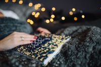 Kaboompics - Woman Reading a Hygge Book Beside Fairy Lights on a Plush Gray Blanket