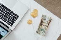 Kaboompics - Dollar Bills and Bitcoin Tokens on Laptop Desk