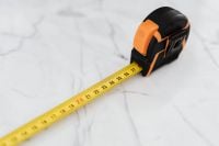 Kaboompics - Close-Up of Black and Orange Tape Measure Case with Yellow Measuring Blade on Marble