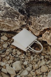 Kaboompics - Structured White Shoulder Bag on Pebbles Beneath a Rock Ledge