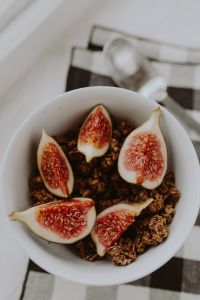 Kaboompics - Vertical Close-Up of Crunchy Granola and Fig Halves in a White Bowl on Neutral Linen