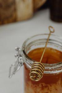 Kaboompics - Macro Honey Dipper Over an Open Glass Jar, Soft-Focus Kitchen Background