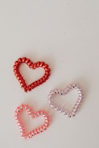 Kaboompics - Three Red and Pink Beaded Hearts on Beige Background with Top Copy Space