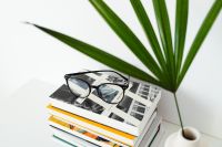 Kaboompics - Reading Glasses on Stacked Books beside a White Vase
