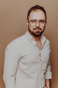 Kaboompics - Close-Up Bearded Man Headshot in Round Glasses Against a Warm Beige Studio Background