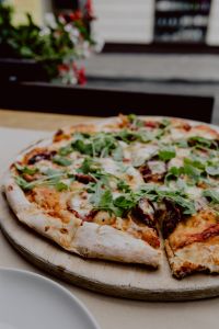Kaboompics - Whole Cheesy Pizza on a Round Wooden Serving Board