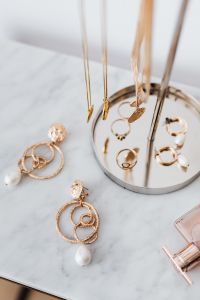 Kaboompics - Gold Chain Necklaces and Pearl Drop Earrings on a Marble Jewelry Stand, Vertical Close-Up