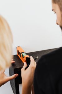 Kaboompics - Two People Aligning a Dark Floating Shelf with a Spirit Level during Home Renovation