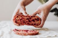 Kaboompics - Hands Holding Halved Beetroot Bread Above Slices