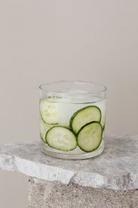 Kaboompics - Cucumber-Infused Water in a Short Glass on Textured Stone, High-Key Vertical Drink Photo with Copy Space