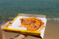 Kaboompics - Woman Enjoying a Pizza Slice Beside the Sea