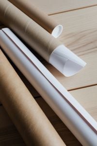 Kraft Cardboard Tubes with Rolled Paper on a Light Wood Background