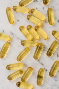Kaboompics - Scattered Golden Softgel Capsules on Marble