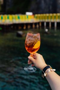 Kaboompics - Aperol Spritz and Wristwatch against Blurred Harbor Rail